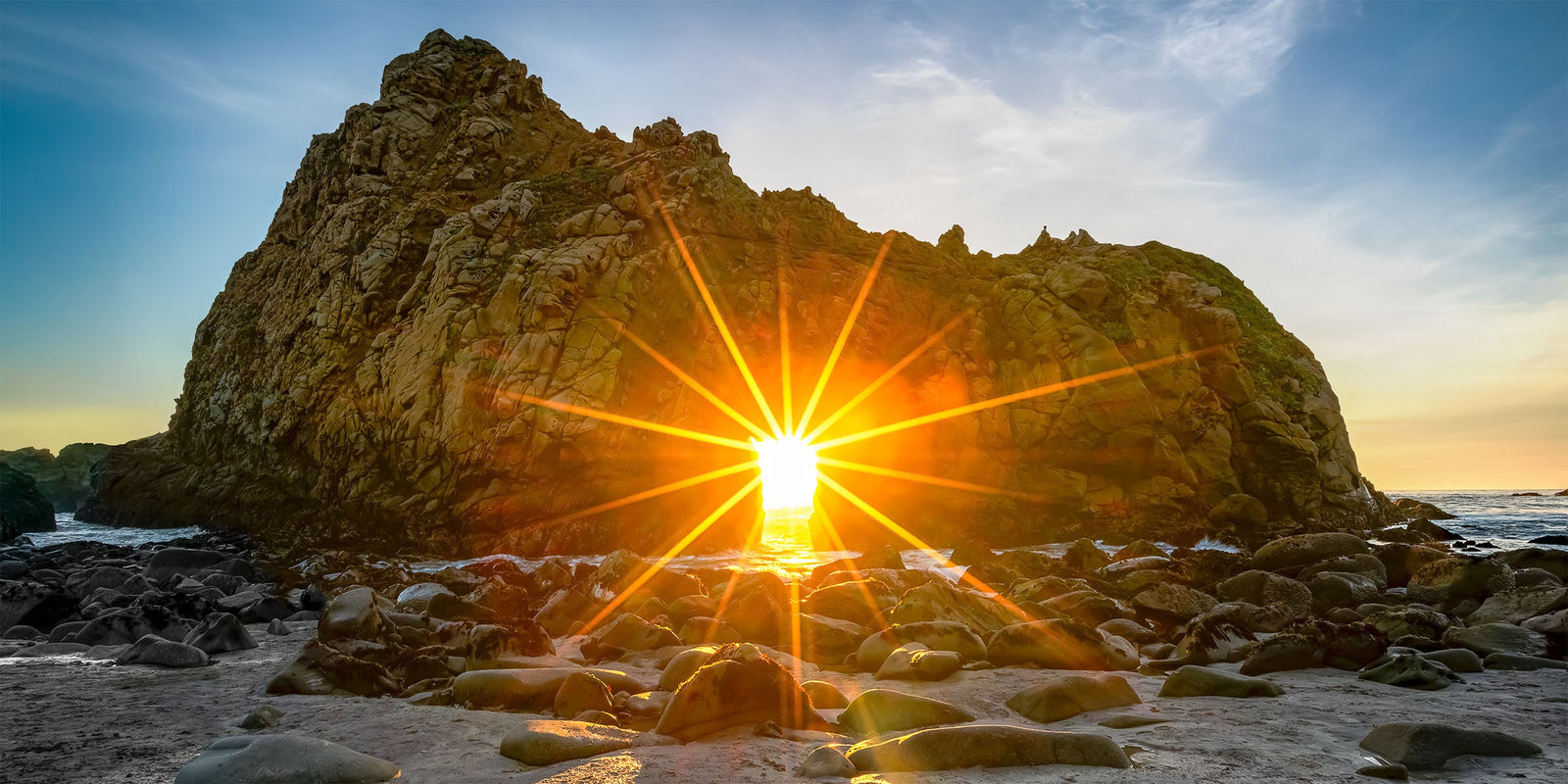 Sunset light streaming through the Keyhole Arch at Pfeiffer Beach, Big Sur, California