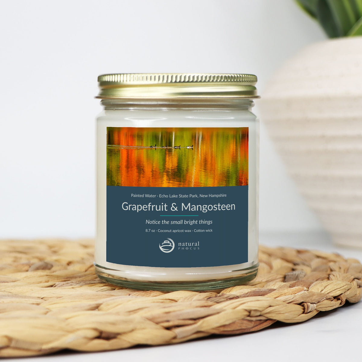 Painted Water Candle in Grapefruit and Mangosteen, a clear glass jar candle with a gold lid, labeled with a photograph of four geese swimming across autumn reflections at Echo Lake State Park, New Hampshire