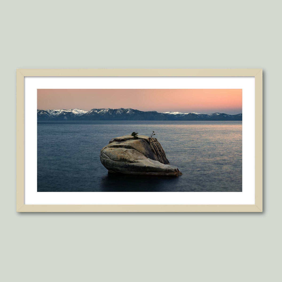 The Heart of Lake Tahoe, a solitary rock with a small tree rising from the still water of Lake Tahoe at sunrise, in a maple frame with a white mat