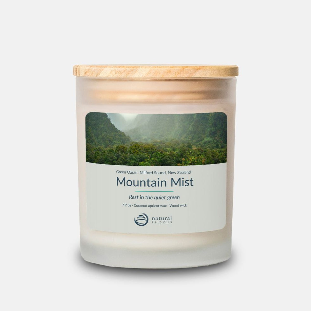 Green Oasis Candle in Mountain Mist, a frosted glass candle with a maple wood lid, labeled with a photograph of mist drifting through a rainforest valley at Milford Sound, New Zealand
