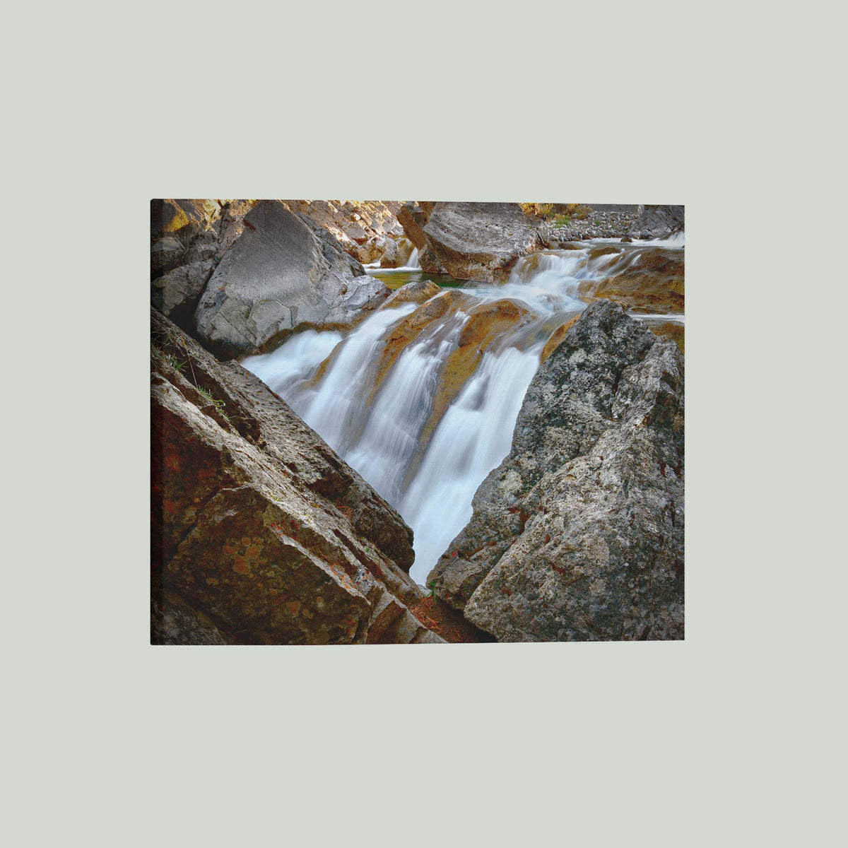 Water Finds a Way, a waterfall flowing between lichen-covered boulders at Hummingbird Falls, Alberta, Canada, as a stretched canvas shown at an angle