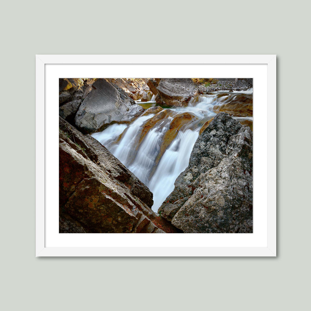 Water Finds a Way, a waterfall flowing between lichen-covered boulders at Hummingbird Falls, Alberta, Canada, in a white frame with a white mat