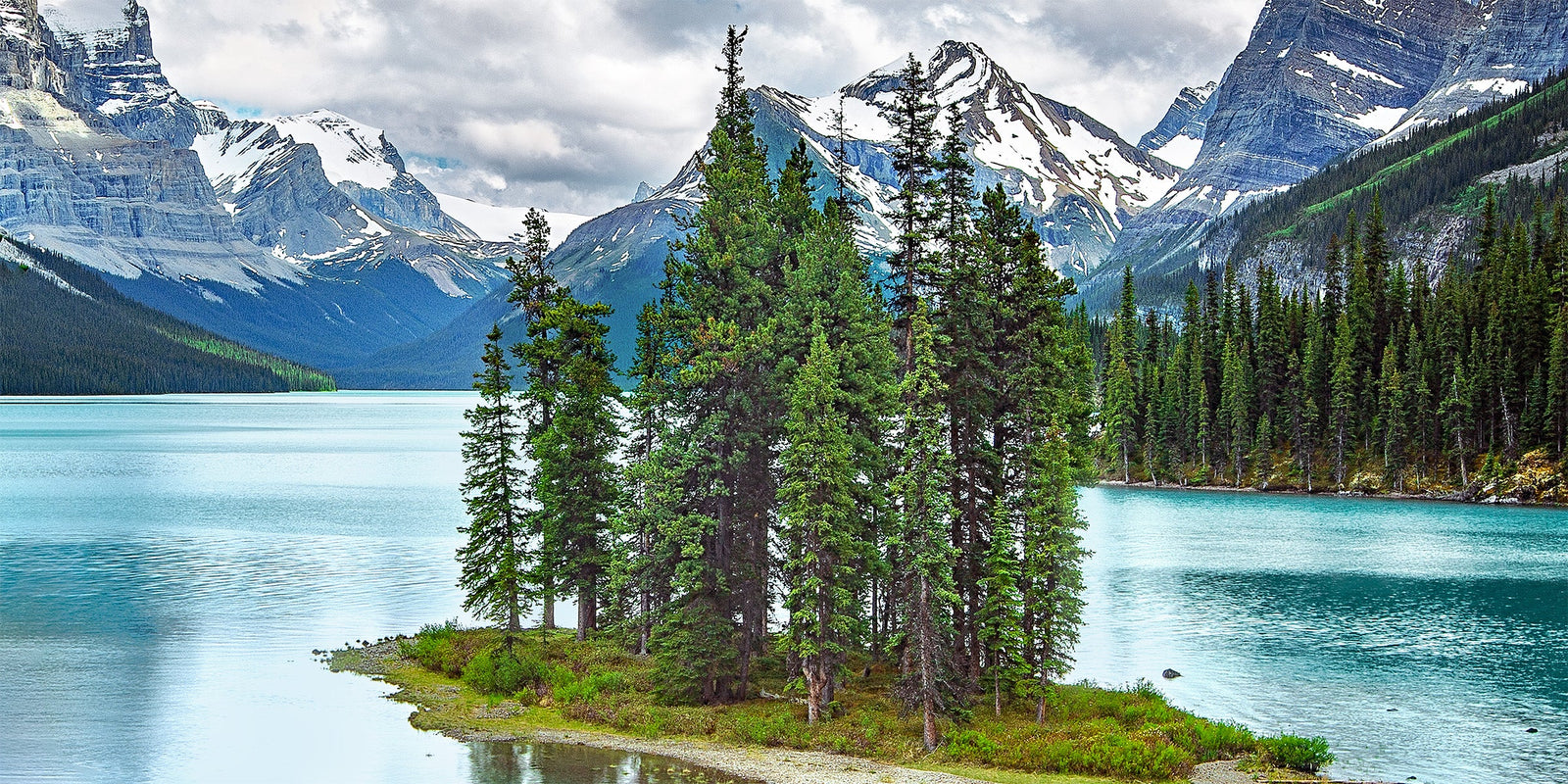Evergreen trees on Spirit Island beneath snow-capped peaks on Maligne Lake, Jasper National Park, Alberta