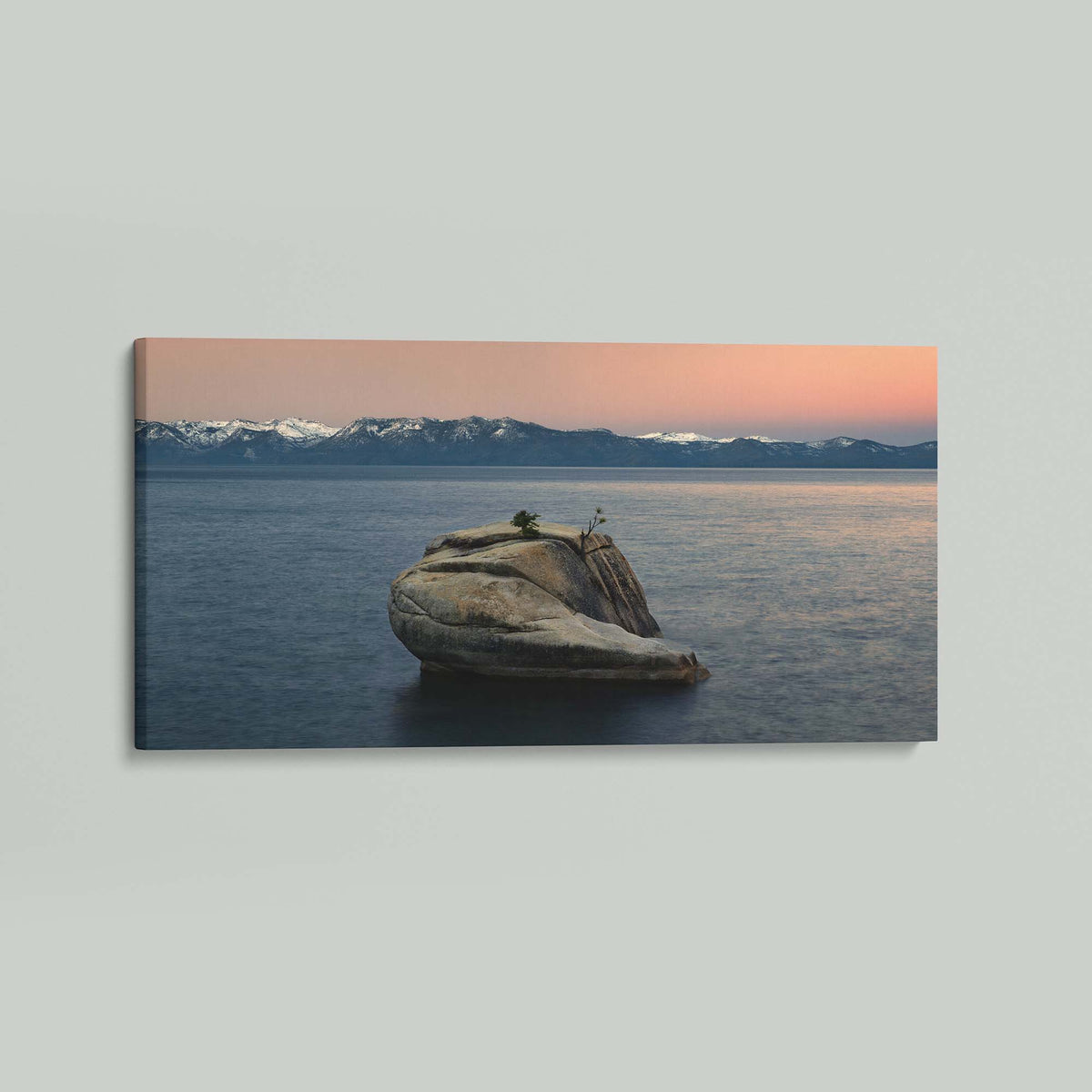 The Heart of Lake Tahoe, a solitary rock with a small tree rising from the still water of Lake Tahoe at sunrise, as a stretched canvas shown at an angle