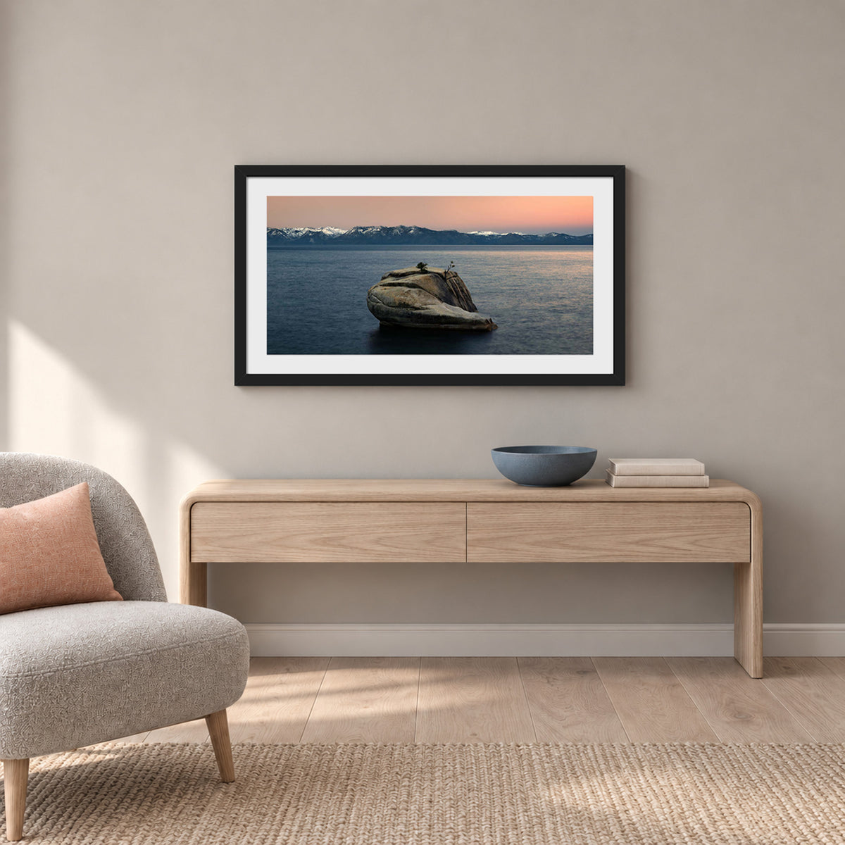 The Heart of Lake Tahoe, a solitary rock with a small tree rising from the still water of Lake Tahoe at sunrise, in a black frame shown in a home setting