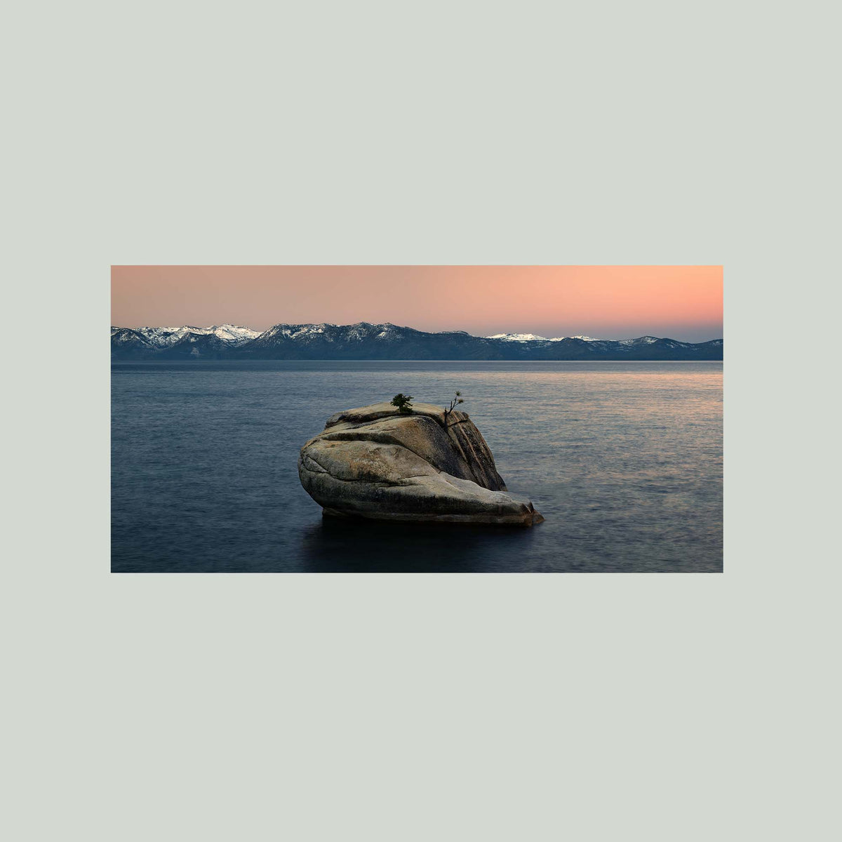 The Heart of Lake Tahoe, a solitary rock with a small tree rising from the still water of Lake Tahoe at sunrise, as an unframed print