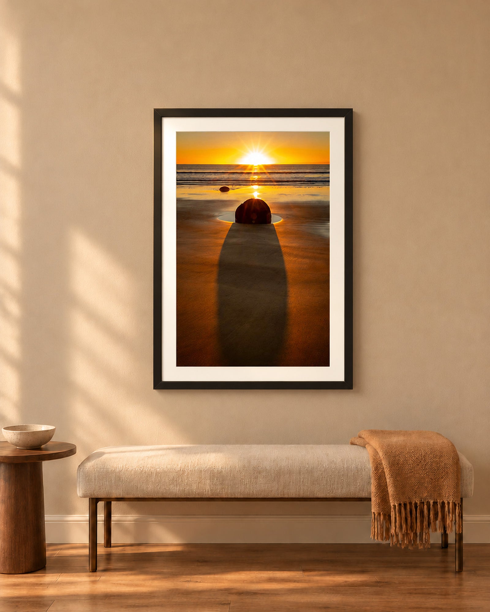 The Patient Stone, a Moeraki Boulder casting a long shadow as the sun rises over the Pacific in Otago, New Zealand, in a black frame shown in a home setting