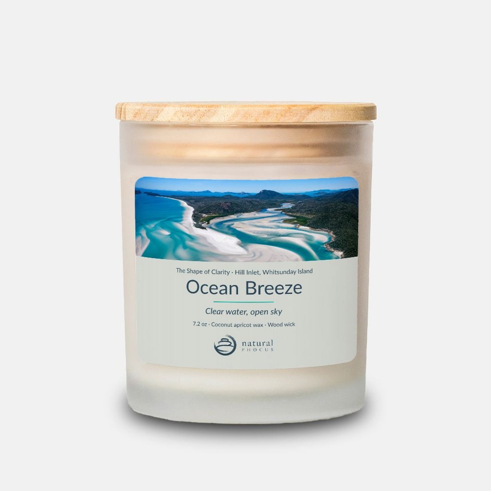 The Shape of Clarity Candle in Ocean Breeze, a frosted glass candle with a maple wood lid, labeled with a photograph of white sand swirling through turquoise water at Hill Inlet, Whitsunday Island, Australia