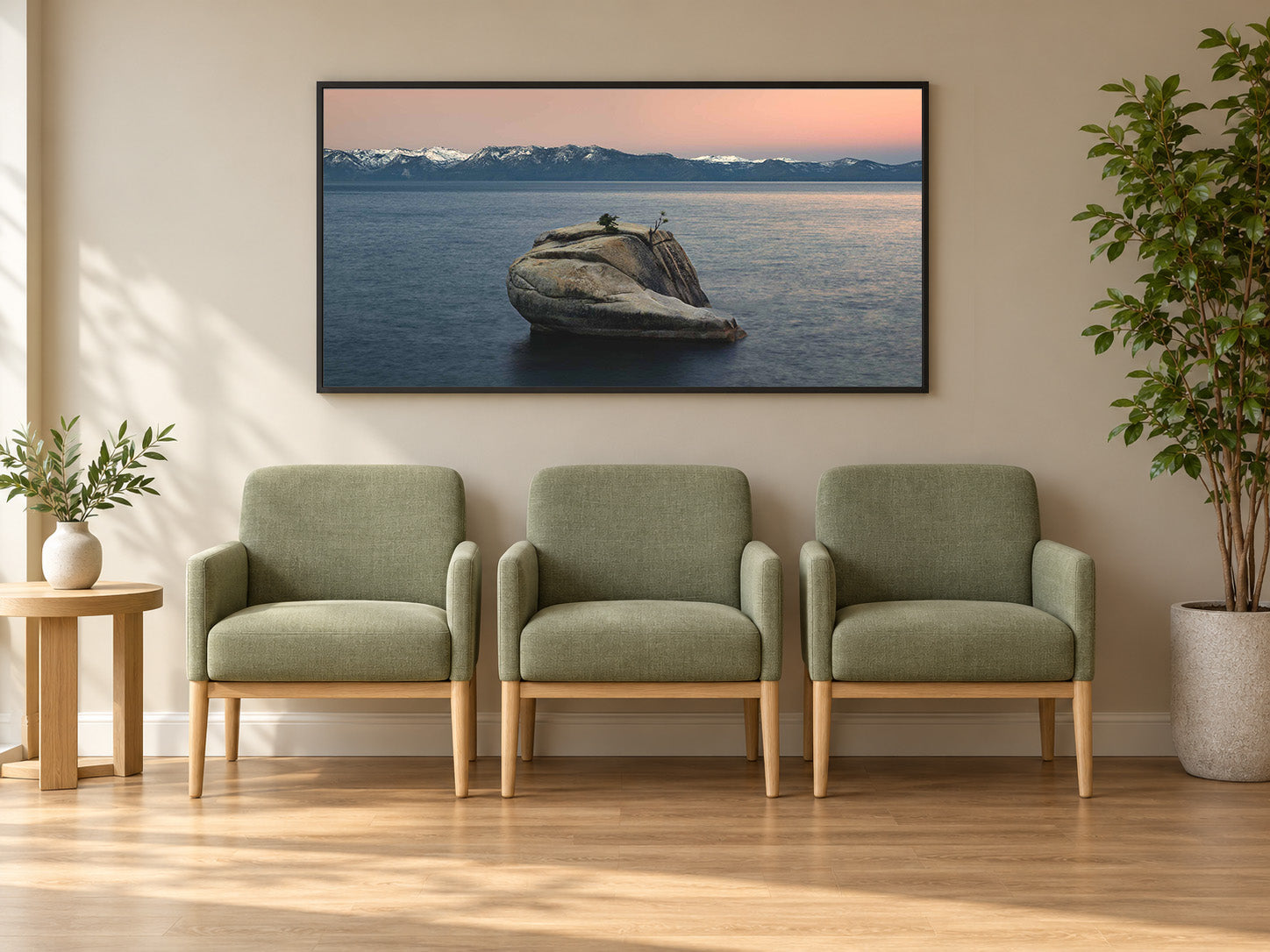 A calm healthcare waiting room with three sage green chairs beneath The Heart of Lake Tahoe, a photograph of Bonsai Rock in still water at dawn, in a black frame