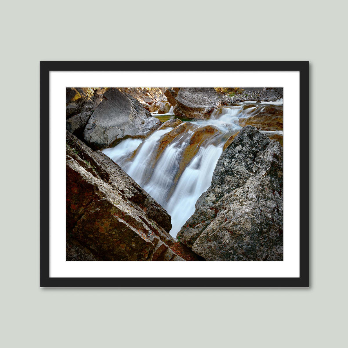 Water Finds a Way, a waterfall flowing between lichen-covered boulders at Hummingbird Falls, Alberta, Canada, in a black frame with a white mat