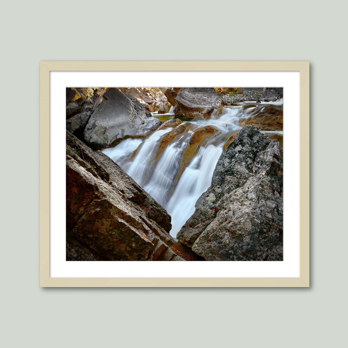 Water Finds a Way, a waterfall flowing between lichen-covered boulders at Hummingbird Falls, Alberta, Canada, in a maple frame with a white mat